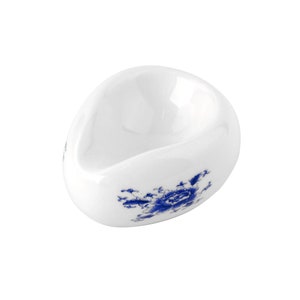 May include: A white ceramic teacup with a blue floral design. The cup is shaped like an egg and has a small lip.