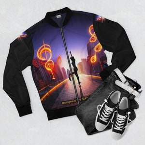 Könnte beinhalten: Schwarze Bomberjacke mit einem farbenfrohen Stadtbild und Noten-Design. Die Jacke hat einen Reißverschluss und zwei Taschen. Der Text "Designed by Stern" ist am unteren Rand der Jacke sichtbar.