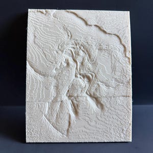 Op de afbeelding: Een rechthoekige, cr&egrave;mekleurige 3D-reli&euml;fkaart met gedetailleerde topografische lijnen. Het verhoogde oppervlak toont een landschap met vari&euml;rende hoogtes, waardoor een textuur ontstaat. De kaart staat tegen een donkere achtergrond.