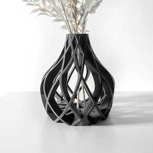 May include: A black, geometric vase with a woven design. The vase is empty and has a round, bulbous shape.