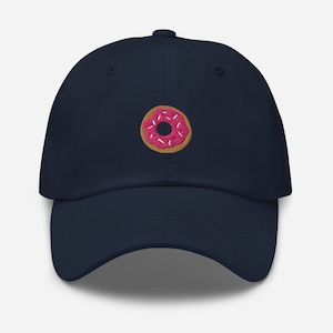 May include: A navy blue baseball cap with a pink and brown donut embroidered on the front.