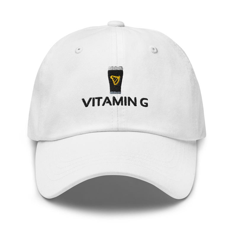 May include: White baseball cap featuring a black and yellow pint of stout graphic and the text "VITAMIN G". The cap has a curved peak and an adjustable strap. A stylish accessory for casual wear.