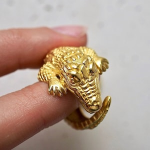 Op de afbeelding: Een gouden alligatorring. De alligator is gedetailleerd met schubben en heeft een textuur.