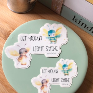 May include: Two watercolor bee stickers with the text "Let your light shine" and "Matthew 5:16" on a light green background.
