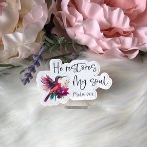 May include: A white sticker with a hummingbird and flowers. The sticker says "He restores my soul" and "Psalm 23:3".