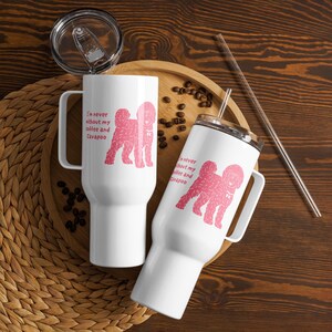 May include: Two white stainless steel tumblers with handles, clear lids, and clear straws. Each tumbler features a pink graphic of a Cavapoo dog and the text "I'm never without my coffee and Cavapoo" printed in a matching pink font on the side.