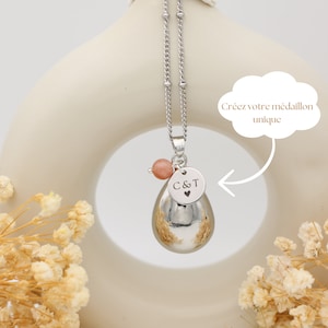 Bola de grossesse argenté en goutte d'eau avec perle  pierre de soleil, médaillon personnalisable gravé 'C&T', sous le slogan 'Créez votre médaillon unique'.