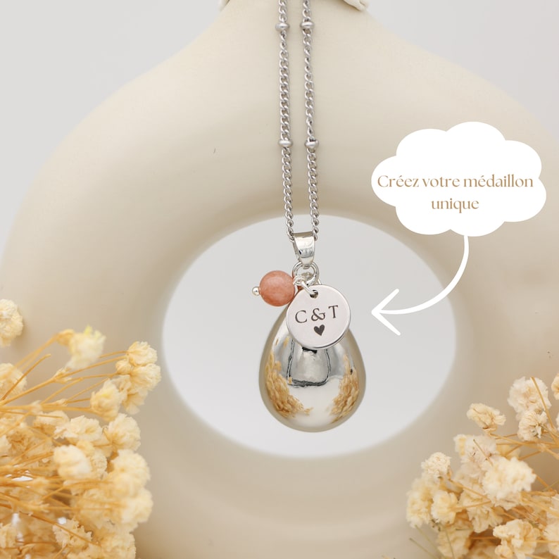 Bola de grossesse argenté en goutte d'eau avec perle  pierre de soleil, médaillon personnalisable gravé 'C&T', sous le slogan 'Créez votre médaillon unique'.
