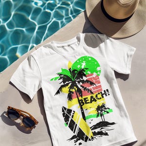 May include: White t-shirt with a colorful beach graphic. The design includes a palm tree, surfboard, and the word "BEACH!" in bold letters. A straw hat and sunglasses are also visible.