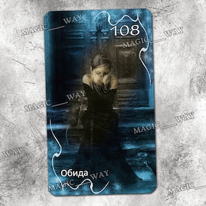 May include: A blue and black tarot card with the number 108 and the word "Obida" in white text. The card features a woman in a black dress sitting on a blue and black background.