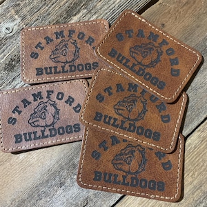 May include: Five brown leather patches with stitched edges. Each patch features a black bulldog mascot with the text "Stamford Bulldogs" in black.