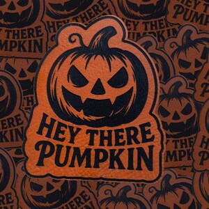 May include: Orange and black Halloween-themed sticker with a pumpkin face and the text "Hey There Pumpkin." The sticker has a leather-like texture and is surrounded by similar stickers.