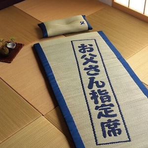 May include: A beige and blue sleeping mat with a blue embroidered Japanese phrase "おやすみん  おやすみん  おやすみん"  and a beige pillow.