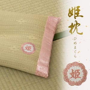 以下が含まれることがあります： 薄いピンクとベージュの枕で、ピンクの刺繍の花と中央に「姫」という日本語の文字が刺繍されています。枕はピンクのサテンの縁取りで、花柄になっています。背景は薄い茶色の畳です。