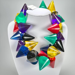 May include: A colorful necklace made of large, pointed, plastic cones. The cones are in various colors, including red, yellow, green, blue, purple, and black.