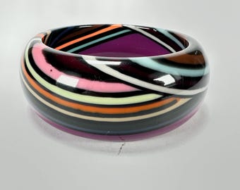 May include: A colourful striped bangle bracelet with a black background and a purple inner rim.