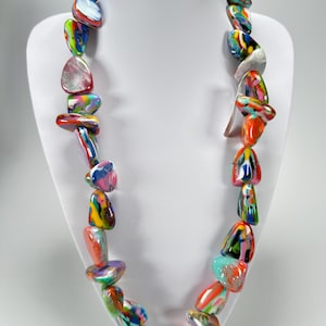 May include: A striking necklace featuring large, multi-coloured beads in shades of red, orange, green, blue, and purple. The necklace is displayed on a white bust, highlighting its unique, irregular bead shapes and vibrant colour palette.