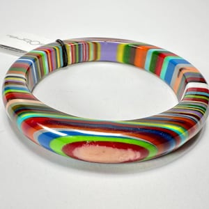 May include: A colourful striped bangle bracelet with a swirl of colours, including red, blue, green, yellow, and white.