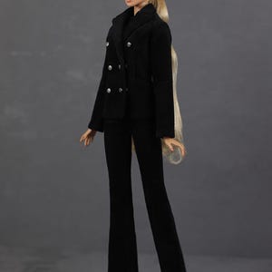 以下が含まれることがあります： ダブルブレストのジャケットとフレアパンツを着用した黒いスーツを着たファッションドール。人形は長い金髪で、銀色のイヤリングをしています。スーツはクラシックなデザインで、さまざまな場面に適しています。