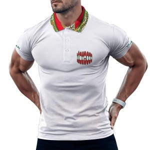 May include: A white short-sleeved polo shirt featuring a red, green, and white patterned collar. The shirt has a three-button placket and a small, circular graphic on the left chest displaying the word Morocco in a stylized red and white font.