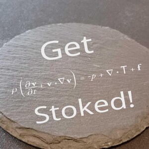 May include: A round, gray slate coaster with the words "Get Stoked!" in white. The coaster also features a mathematical equation. The coaster is a unique and decorative item.