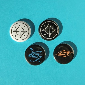 Könnte beinhalten: Vier runde schwarze und weiße Knöpfe mit verschiedenen grafischen Designs. Die Knöpfe zeigen einen schwarzen und weißen Kompass, einen schwarzen und weißen Stern, ein schwarzes und blaues Auge und einen schwarzen und orangefarbenen Wirbel.