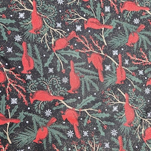 May include: A fabric with a repeating pattern of red cardinals, green holly leaves, white snowflakes, and berries on a black background. The design has a festive, wintery theme.