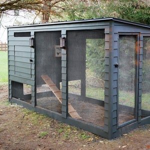 May include: A grey wooden chicken coop with a wire mesh enclosure and a ramp for the chickens to enter. The coop has a door on the side and a sign that says "Beware of Chickens".