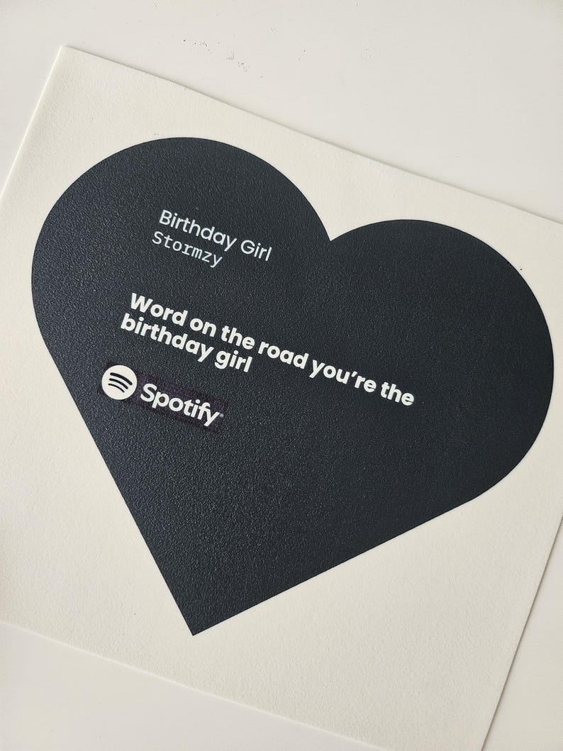 Pode incluir: Um cart&atilde;o branco com um design em forma de cora&ccedil;&atilde;o preto. O cora&ccedil;&atilde;o cont&eacute;m o texto "Birthday Girl Stormzy" e "Word on the road you're the birthday girl" com o logotipo do Spotify. Um item com tema de anivers&aacute;rio.
