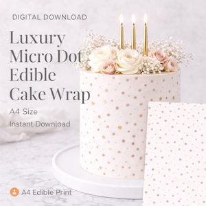 Op de afbeelding: Een ronde witte taart met gouden microstippen, versierd met witte en roze rozen, gipskruid en gouden kaarsen. De taart staat op een witte standaard. De tekst luidt "Luxury Micro Dot Edible Cake Wrap".