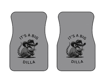 May include: A set of two gray car floor mats with a black and white illustration of a cartoon rodent wearing a cowboy hat. The text "It's a Big Dilla" is printed on each mat.