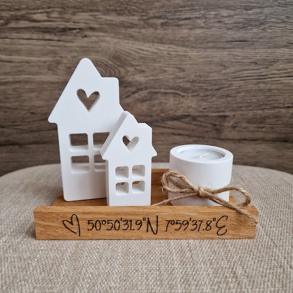 May include: White wooden house candle holder with a small white candle and a wooden base with the coordinates "50°50'31.9"N 75°59'37.8"E" engraved on it.