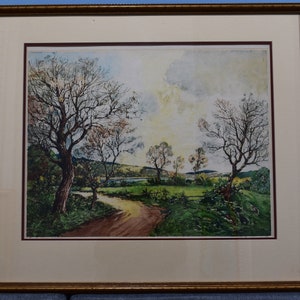 May include: A framed landscape painting depicting a country road winding through a field with bare trees and a cloudy sky. The painting is done in a watercolor style with shades of green, brown, and blue.