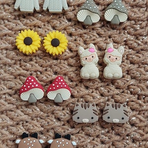 May include: Set of 10 colourful silicone charms featuring various designs, including mushrooms, sunflowers, llamas, cats, and deer. These charms are perfect for adding a touch of whimsy to your belongings.