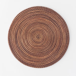 May include: A round, woven brown placemat with a concentric circle pattern.