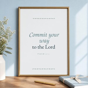 Könnte beinhalten: Ein gerahmter Kunstdruck mit dem Text Commit your way to the Lord PSALM 37:5 in dunkelblauer Serifenschrift auf weißem Hintergrund. Der Druck befindet sich in einem dünnen goldenen Metallrahmen mit dekorativen horizontalen Linien ober- und unterhalb.
