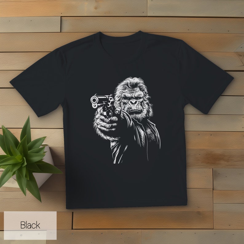 以下が含まれることがあります： 銃を持ったゴリラの白いグラフィックがプリントされた黒いTシャツ