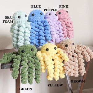 May include: A collection of seven crocheted octopus plush toys with black plastic eyes. The colors are labeled as SEA FOAM, BLUE, PURPLE, PINK, GREEN, YELLOW, and BROWN. Each octopus features a round head and eight curly, textured tentacles.