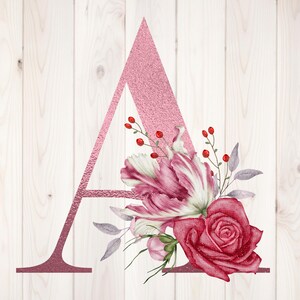 Puede incluir: Una letra "A" decorativa en rosa brillante, adornada con un arreglo floral de acuarela. Las flores incluyen una rosa roja, tulipanes rosas y blancos y bayas rojas, sobre un fondo de vetas de madera blanca.
