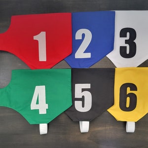May include: Six fabric numbered flags in different colors. The flags are red, blue, white, green, black, and yellow. The numbers on the flags are 1, 2, 3, 4, 5, and 6.