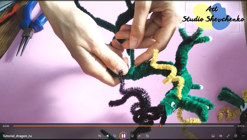 Puede incluir: Un drag&oacute;n de limpiapipas verde, amarillo y negro est&aacute; siendo ensamblado. El drag&oacute;n tiene una cola larga, alas y una cabeza con ojos. El drag&oacute;n est&aacute; siendo sostenido por las manos de una persona. El texto "Art Studio Shevchenko" es visible en la esquina superior derecha de la imagen.