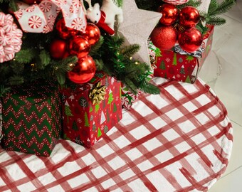 May include: A decorated Christmas tree with red ornaments, white star decorations, and wrapped gifts. A red and white plaid tree skirt covers the base of the tree, creating a festive holiday scene.