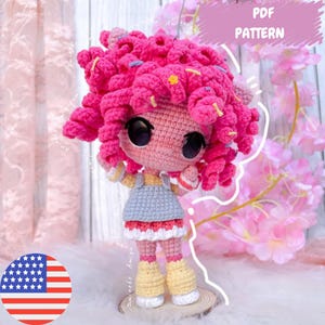 Puede incluir: Una muñeca de ganchillo hecha a mano con cabello rizado rosa brillante, ojos negros grandes y tez rosa claro. La muñeca viste un vestido azul claro con ribete blanco y rojo, y botas amarillas. Incluye el texto "PDF PATTERN".
