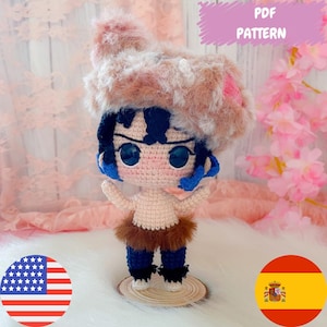 Puede incluir: Muñeca de ganchillo de un personaje con pelo y ojos azules, con un sombrero y pantalones cortos peludos. La muñeca está sobre una base de madera. La imagen incluye el texto "PDF PATTERN" y la bandera americana.