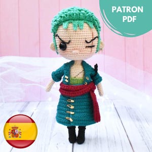Puede incluir: Muñeco de ganchillo de un personaje con pelo verde, una cicatriz y un parche en el ojo negro. El muñeco lleva una chaqueta verde azulado, una faja roja y botas negras. El texto "PATRON PDF" es visible. Una bandera española está en la esquina inferior izquierda.