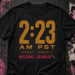 May include: A black short-sleeve t-shirt featuring a distressed gold graphic that reads 2:23 AM PST, followed by TUESDAY JANUARY 3 and the red text WELCOME, CRAWLER with a small staircase icon next to the final word on the front of the garment.