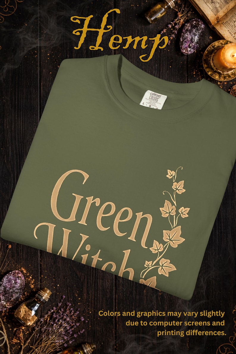 Peut inclure: T-shirt vert olive avec l'inscription "Green Witch" en lettres dor&eacute;es, accompagn&eacute;e d'un motif de feuilles et de vigne dor&eacute;es. Le mot "Hemp" est au-dessus en lettres dor&eacute;es.