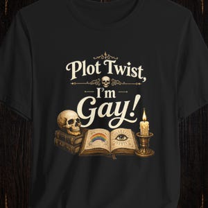 May include: Black t-shirt with the text "Plot Twist, I'm Gay!" in a vintage font. The design includes a skull, books, an open book with a rainbow and eye, and a candle.
