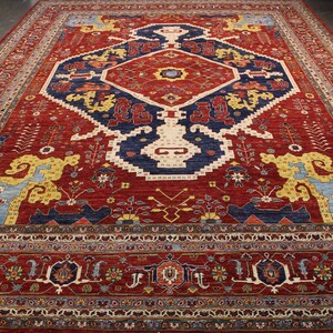 May include: A traditional Persian rug with a red background and intricate blue, yellow, and white patterns. The rug features a central medallion with a geometric design and floral motifs throughout.
