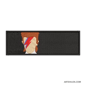 Puede incluir: Parche bordado en blanco y negro con una imagen estilizada de David Bowie con su característico maquillaje de rayo.